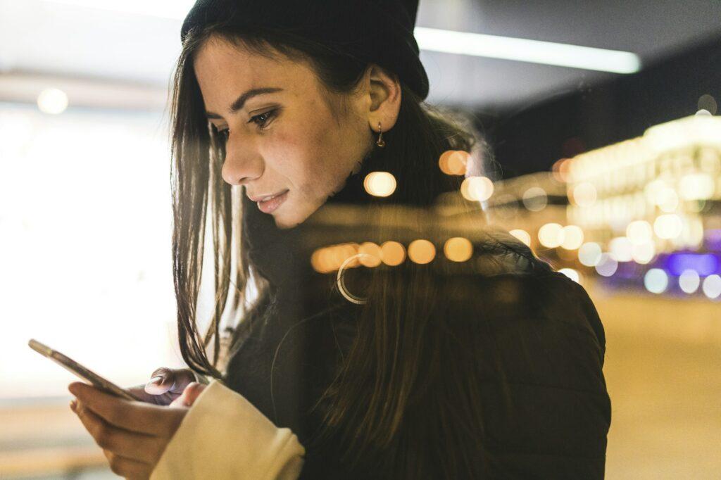 Russia, Moscow, woman in the city at night looking at smartphone