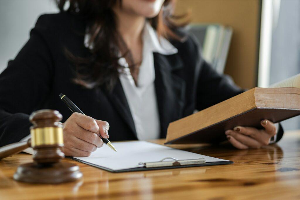 Female lawyer working in a law office reading a law book on the desk.