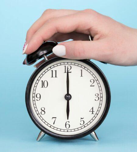 Female hand clamps the alarm clock