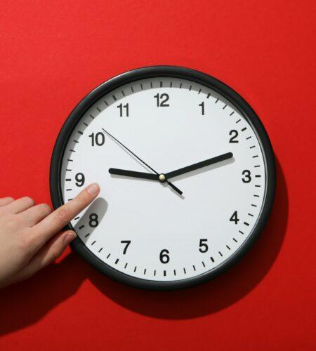 Concept of time change with clock on red background